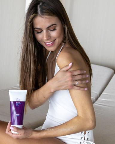 Meisje brengt Moisturizing Body Cream aan op haar arm voor een verzorgde, gehydrateerde huid.